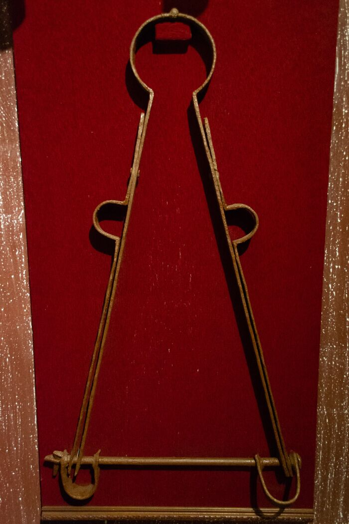 Medieval t*****e device made of rusted iron displayed against red velvet, illustrating shocking t*****e methods from history.